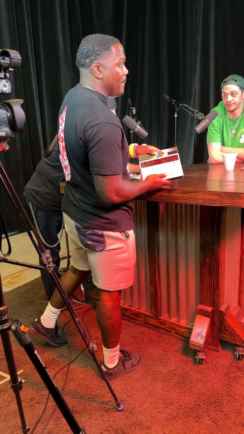 Nicholas Smith holding a slate at the interview table with Pete Davidson